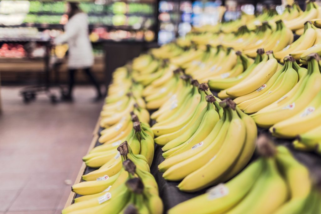 A side view of bunches of bananas lined up on a grocery shelf