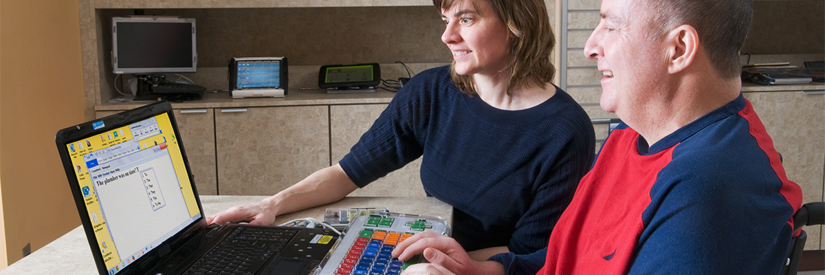 Therapist and patient working at a computer and practicing cognitive skills using adapted keyboard