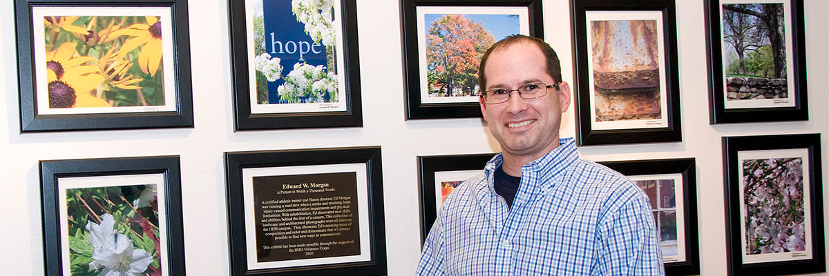 Man in front of framed photos from Helen Hayes Hospital