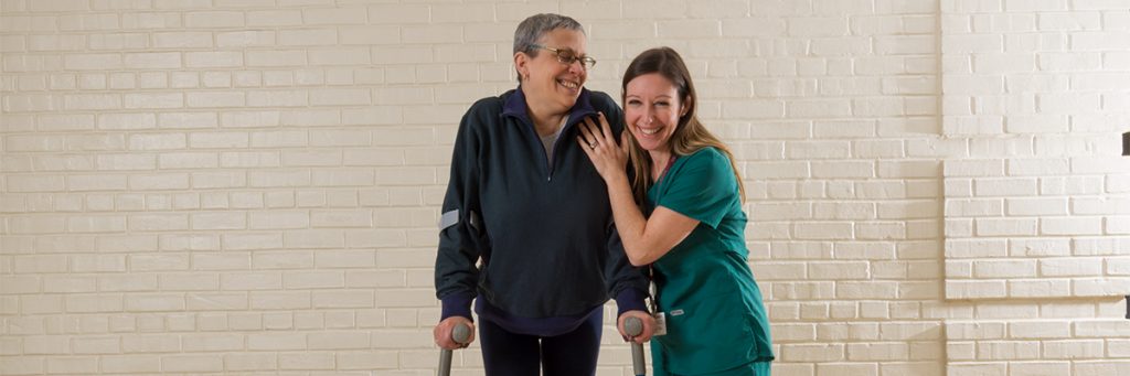 Patient using forearm crutches with therapist walking alongside her