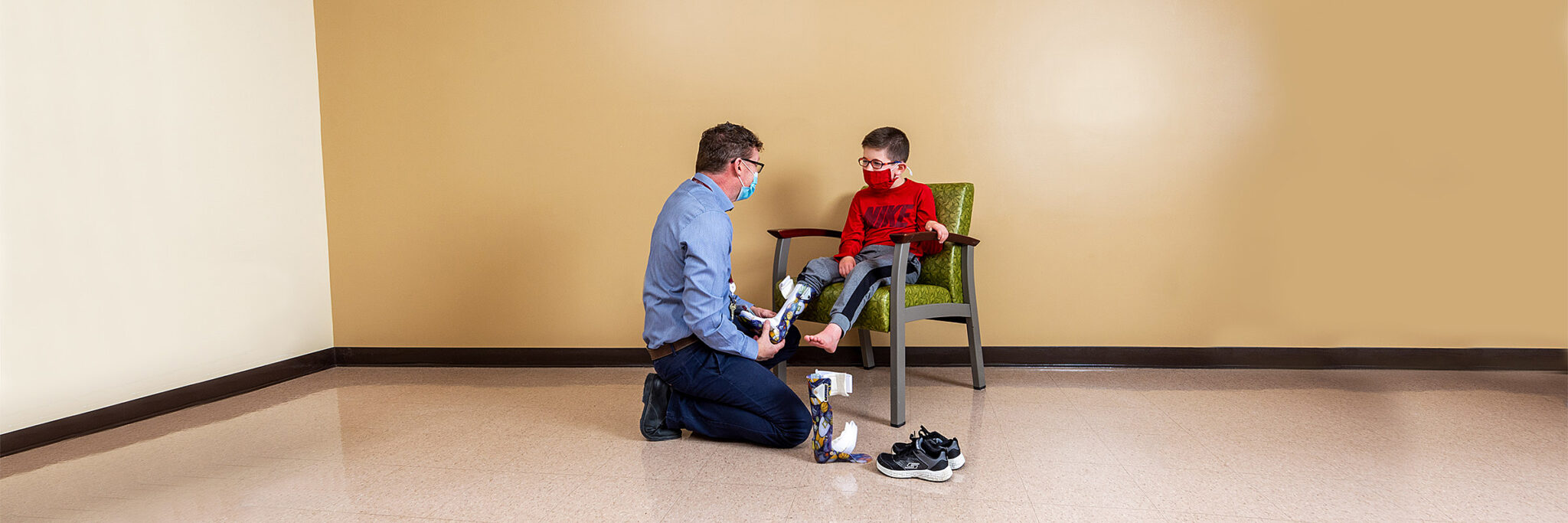 Prosthetist fitting prosthetic leg onto boy