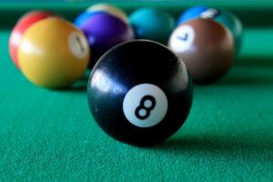 Pool balls on a pool table, with the 8 ball at the forefront.