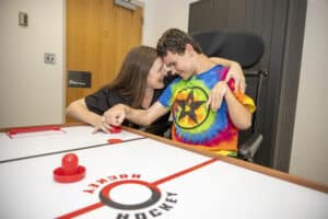 Female therapist with a male pediatric patient engaging in therapy at an air hockey table.