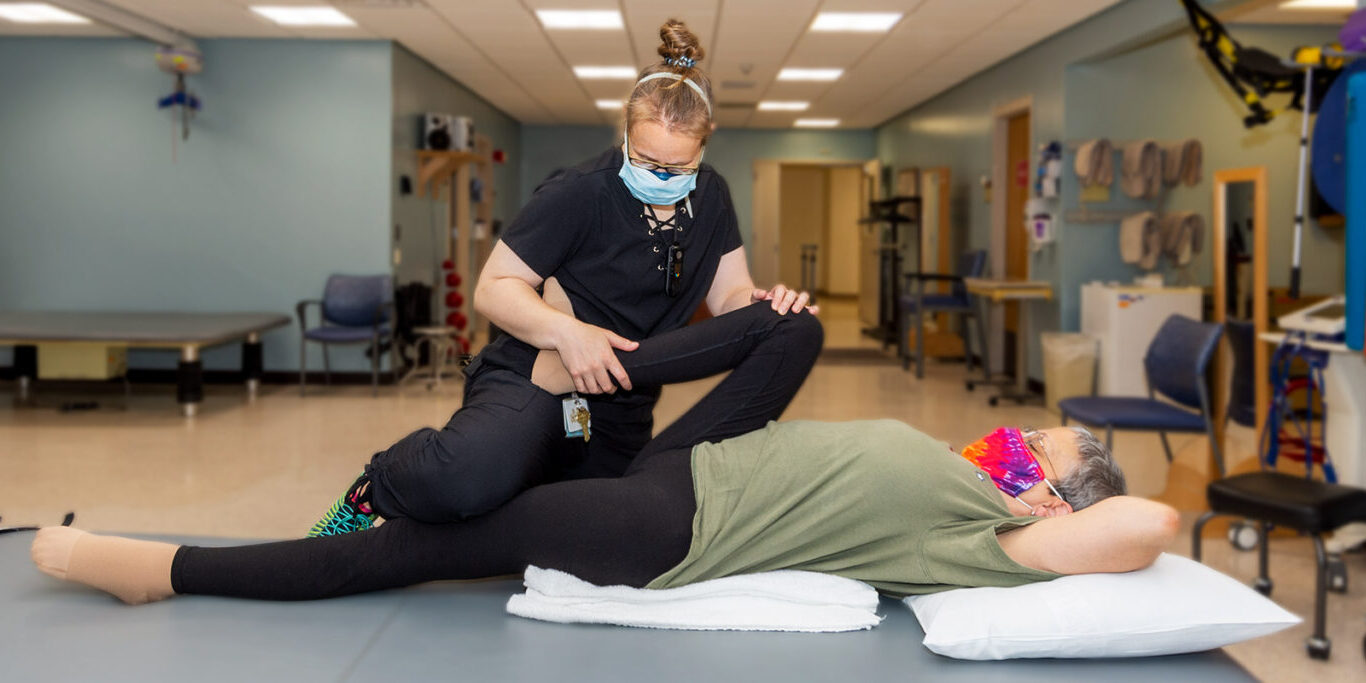 Physical therapist assisting patient with therapy exercise