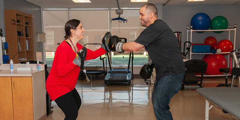 Therapist and patient boxing during outpatient neurological occupational therapy session