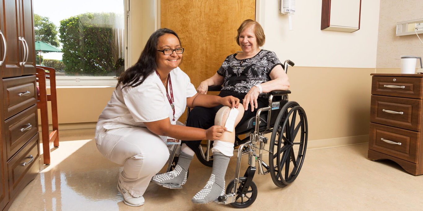 Nurse assisting patient in a wheelchair with bandage